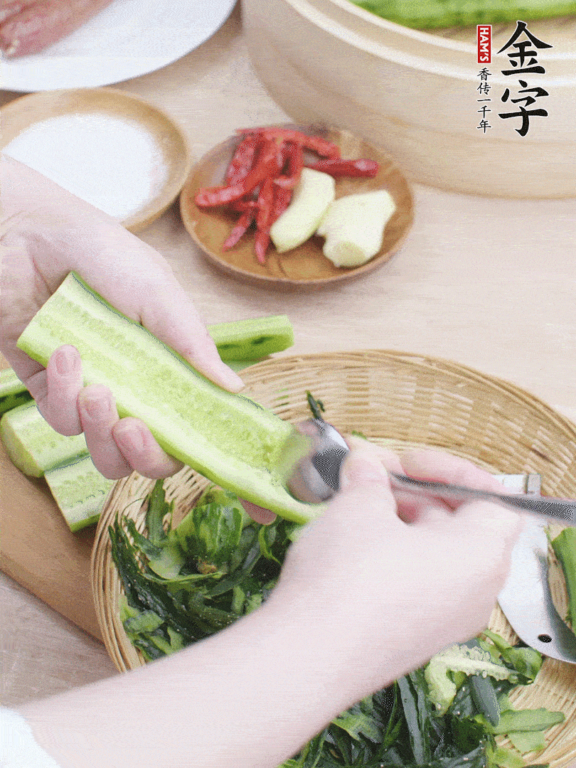 黃瓜削皮，對半切開，勺子挖去內(nèi)瓤，斜刀切片。青蒜斜刀切段。
