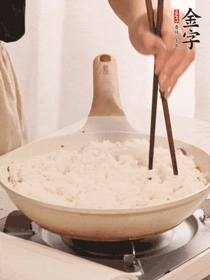 把瀝干水分的米飯均勻鋪在上面，筷子戳幾個(gè)洞，以便透氣，轉(zhuǎn)小火蓋上蓋子燜至水分收干，大概10分鐘。